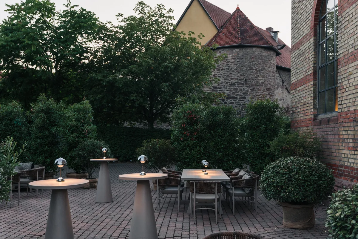 Stehtische mit Tischlampen im Innenhof in der Abenddämmerung