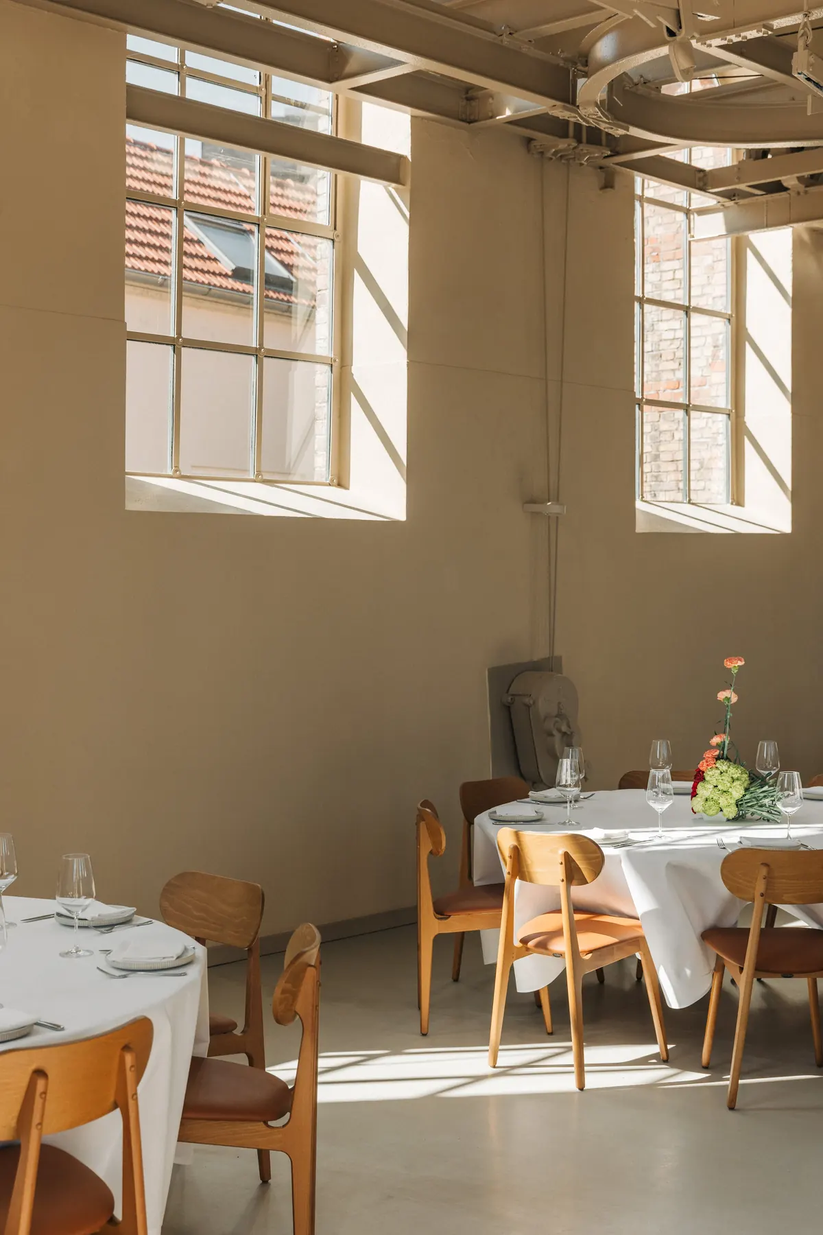 Hohe Fenster und gedeckte runde Tische im Loft
