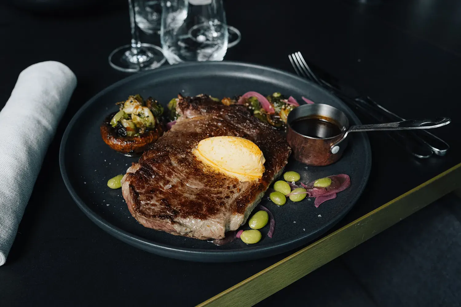 Dry-Aged-Steak mit Kräuterbutter auf dunklem Teller