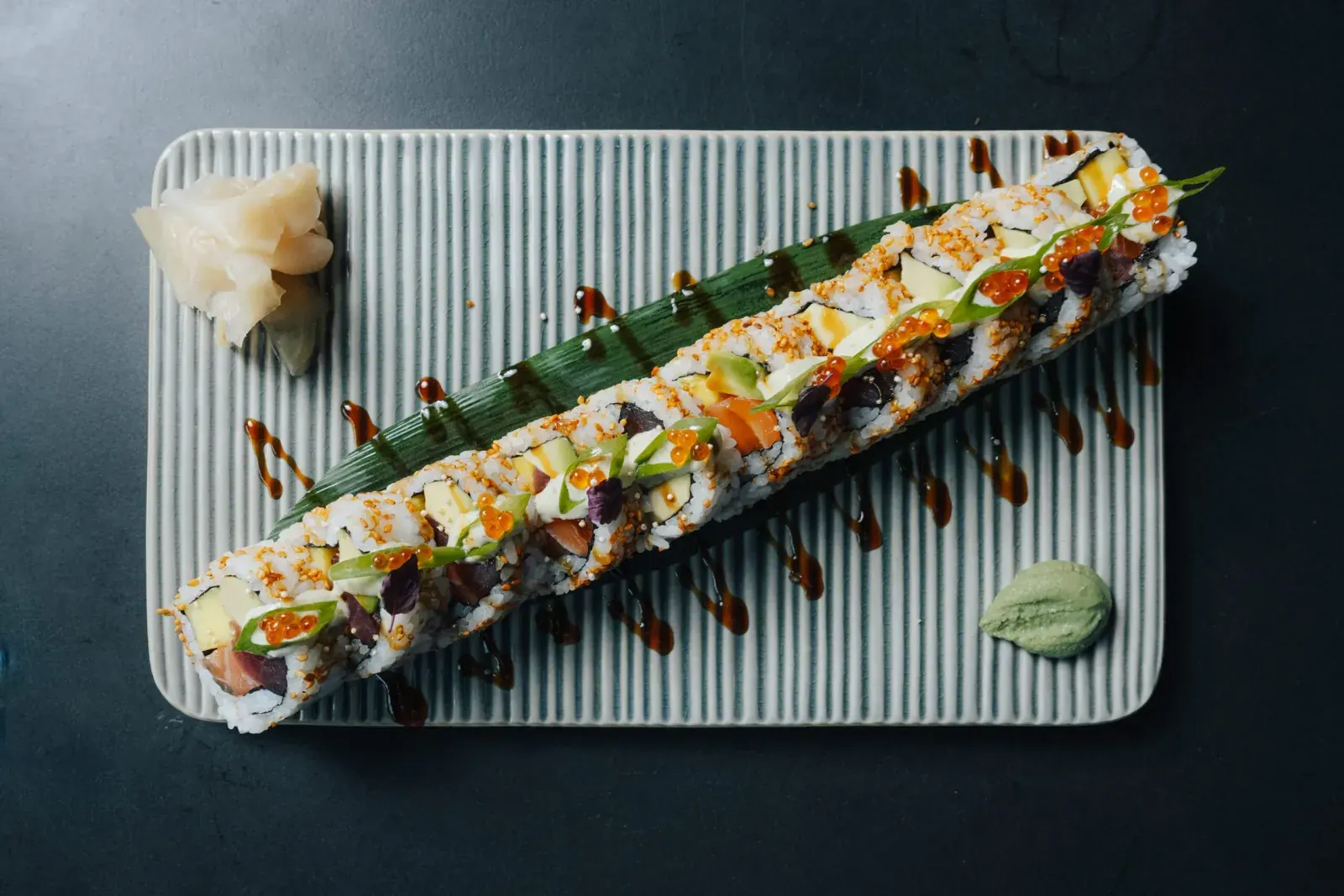 Signature Roll auf geriffelter Platte, daneben Ingwer und Wasabi