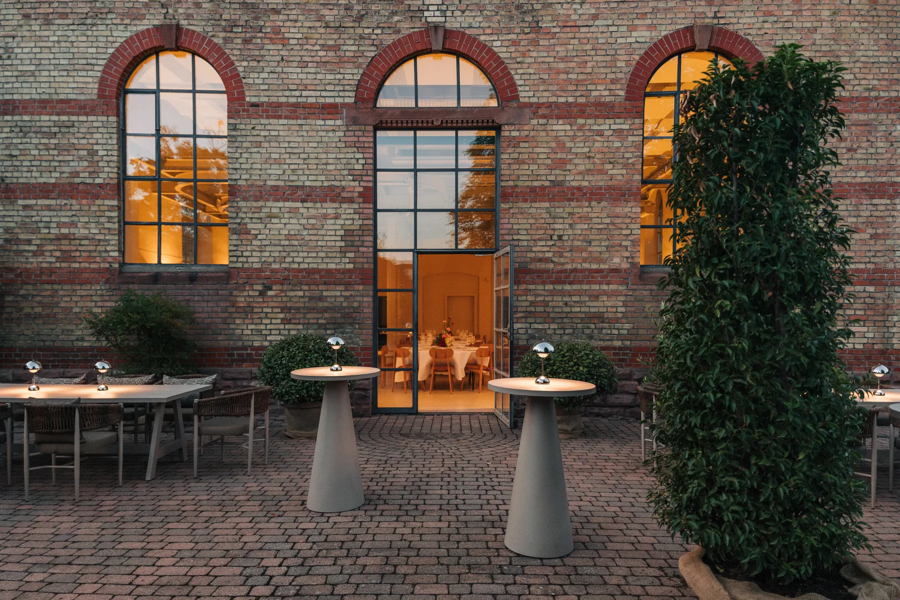 Innenhof des l'ab in der Abenddämmerung mit warm erleuchteten Bogenfenstern