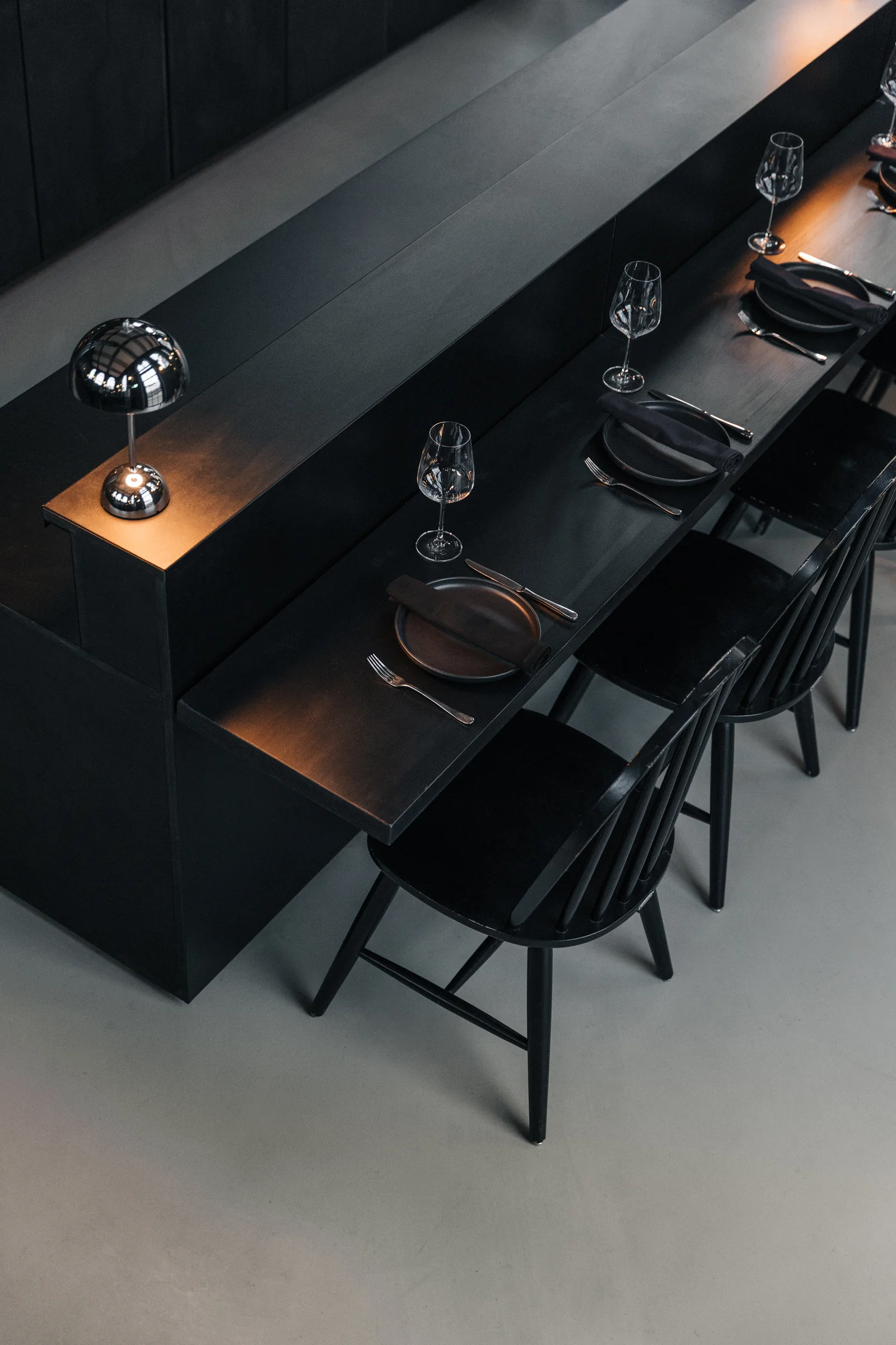 Schwarze Theke mit Gedecken und silberner Tischlampe