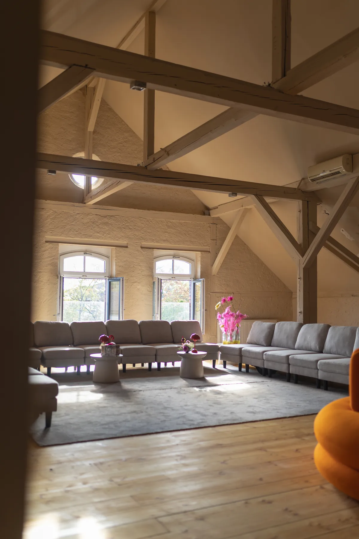 Blick in den Salon des l'ab mit Holzbalken und Sofas